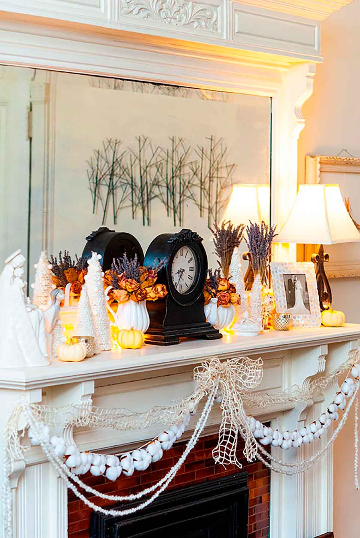 A mantle decorated with a clock, various Christmas decorations and cotton garland.