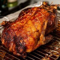 A roasted duck on lace table cloth, garnished with thyme.