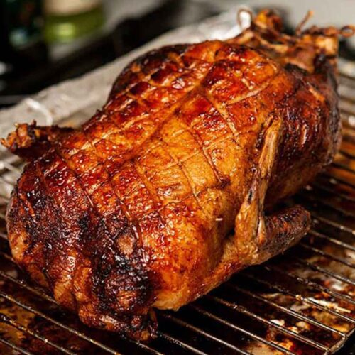 A roasted duck on lace table cloth, garnished with thyme.