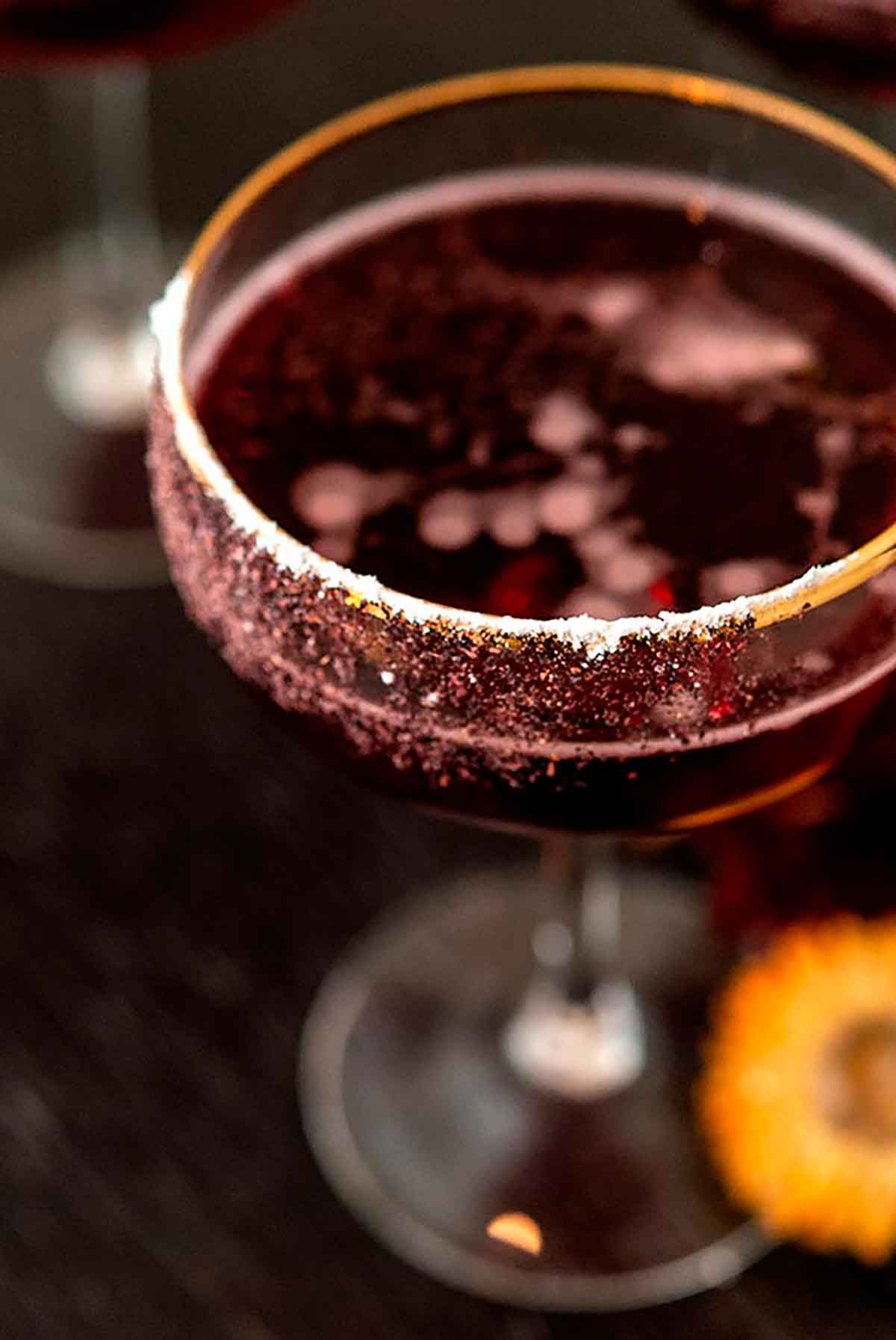 A powdered sugar and hibiscus powder garnish on the side of a cocktail.