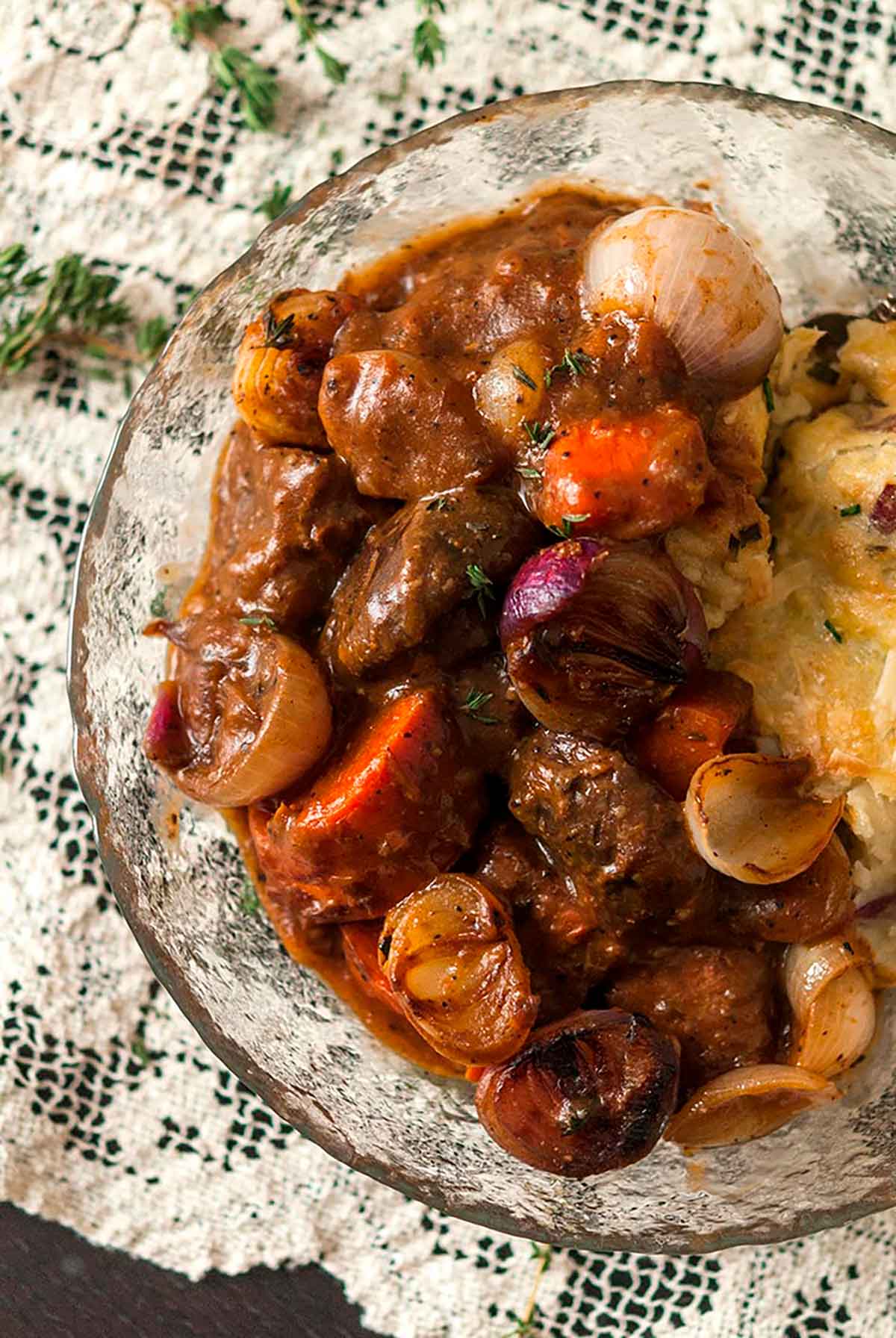 A bowl of beef bourguignon on a lace table cloth.