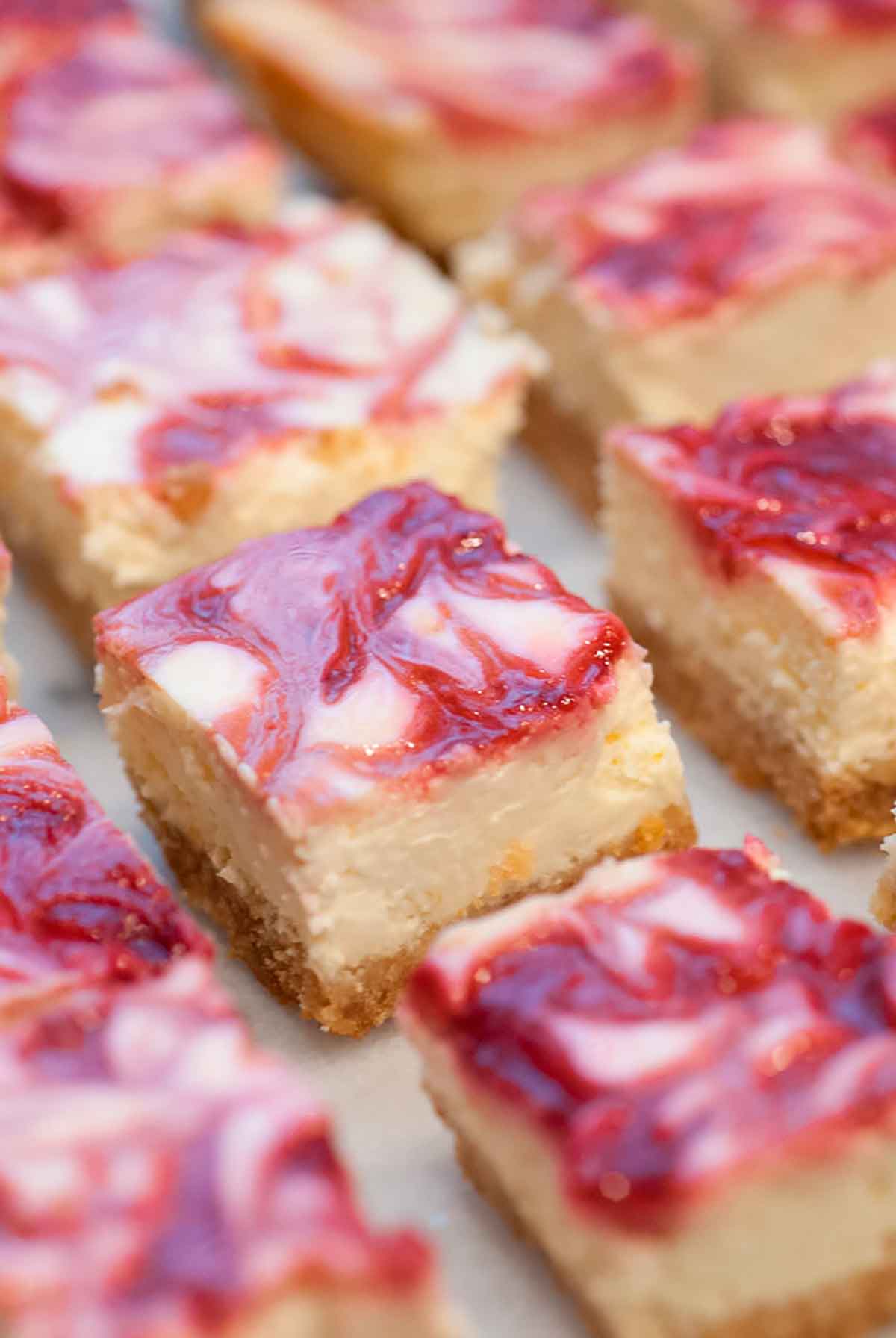 Raspberry marbled lemon cheesecake bars on a marble table.