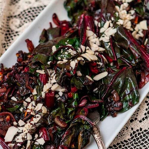 A plate of Swiss chard on a lace table cloth.