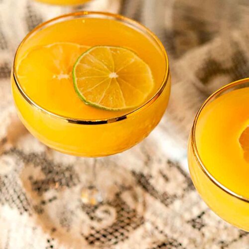 A bowl of pineapple punch in a punch bowl, with an ice ring filled with limes and jalapeños in the center.