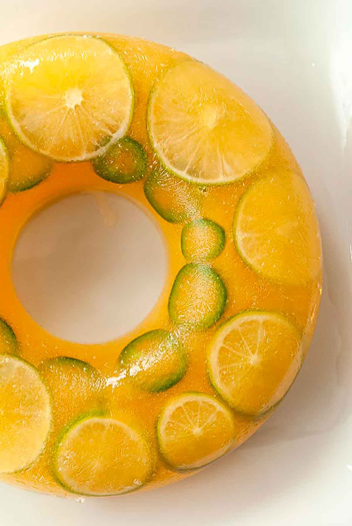 A ring of pineapple ice with limes and jalapeños frozen inside on a large dish.