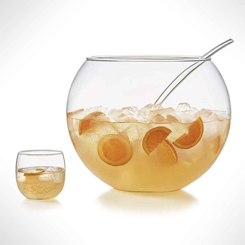 A punch bowl beside a glass of punch.