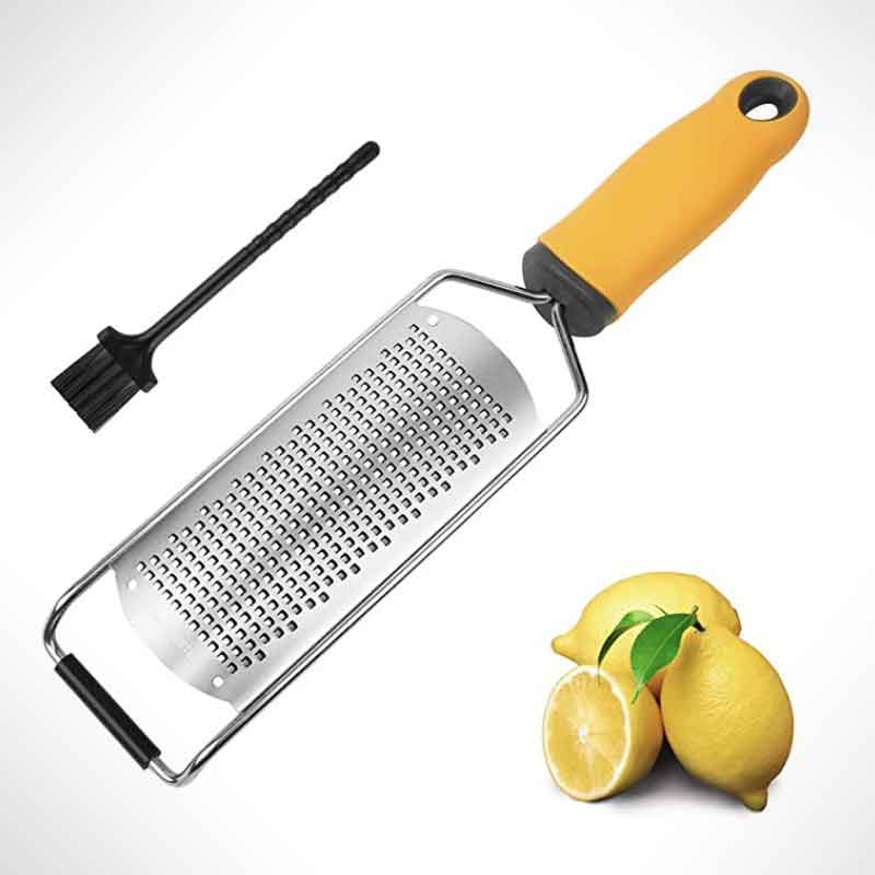 A lemon zester beside a small brush and 3 lemons.