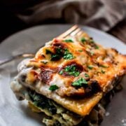 A slice of mushroom, spinach and artichoke lasagna on a plate.