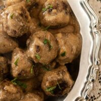 Swedish meatballs in a silver bowl on a lace tablecloth.