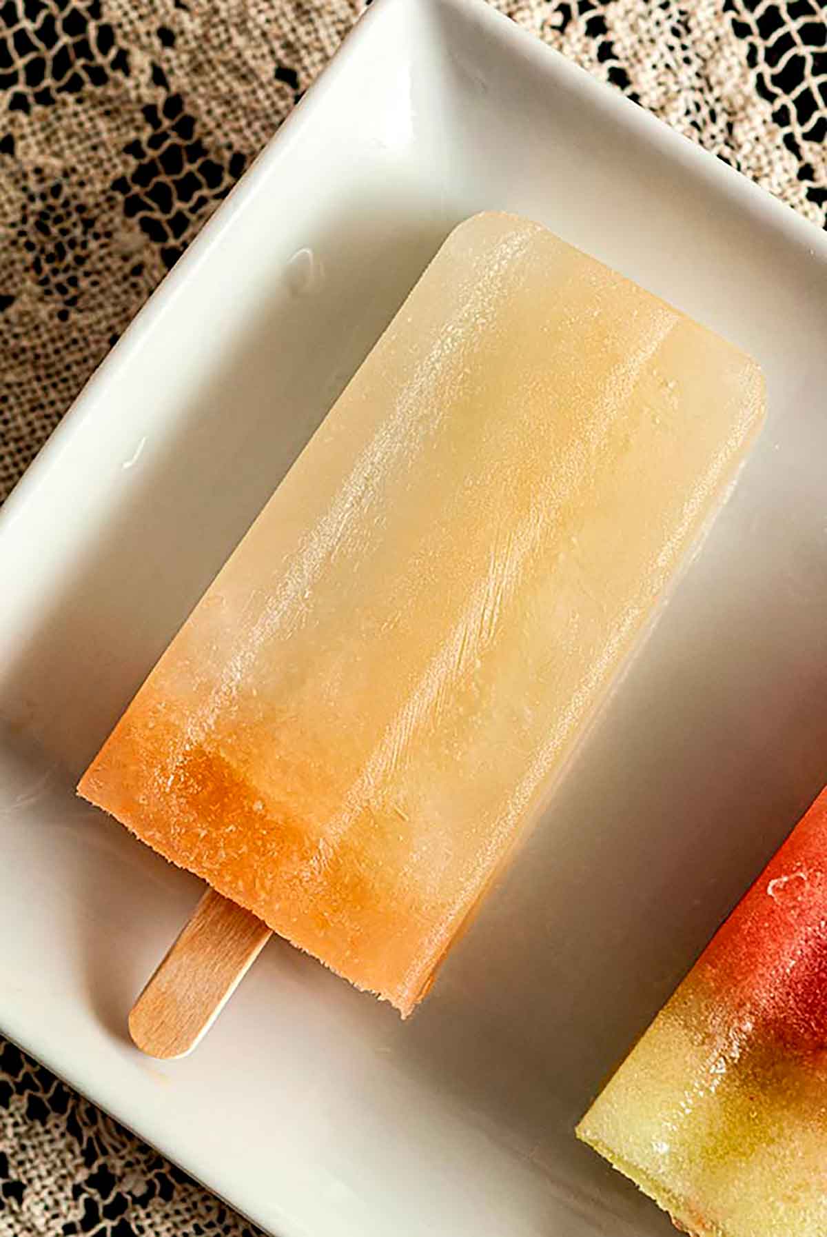 A lemon basil ice pop on a white plate.