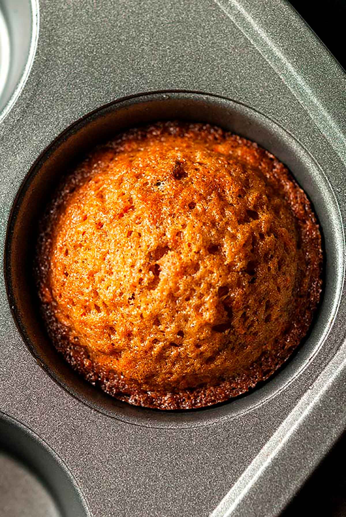 A perfectly cooked cupcake in a tin with brown edges.