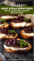 6 steak appetizers on a marble slate, garnished with tiny grapes, arugula and dripping cheese.