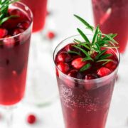 4 cranberry mimosas, garnished with cranberries and rosemary.