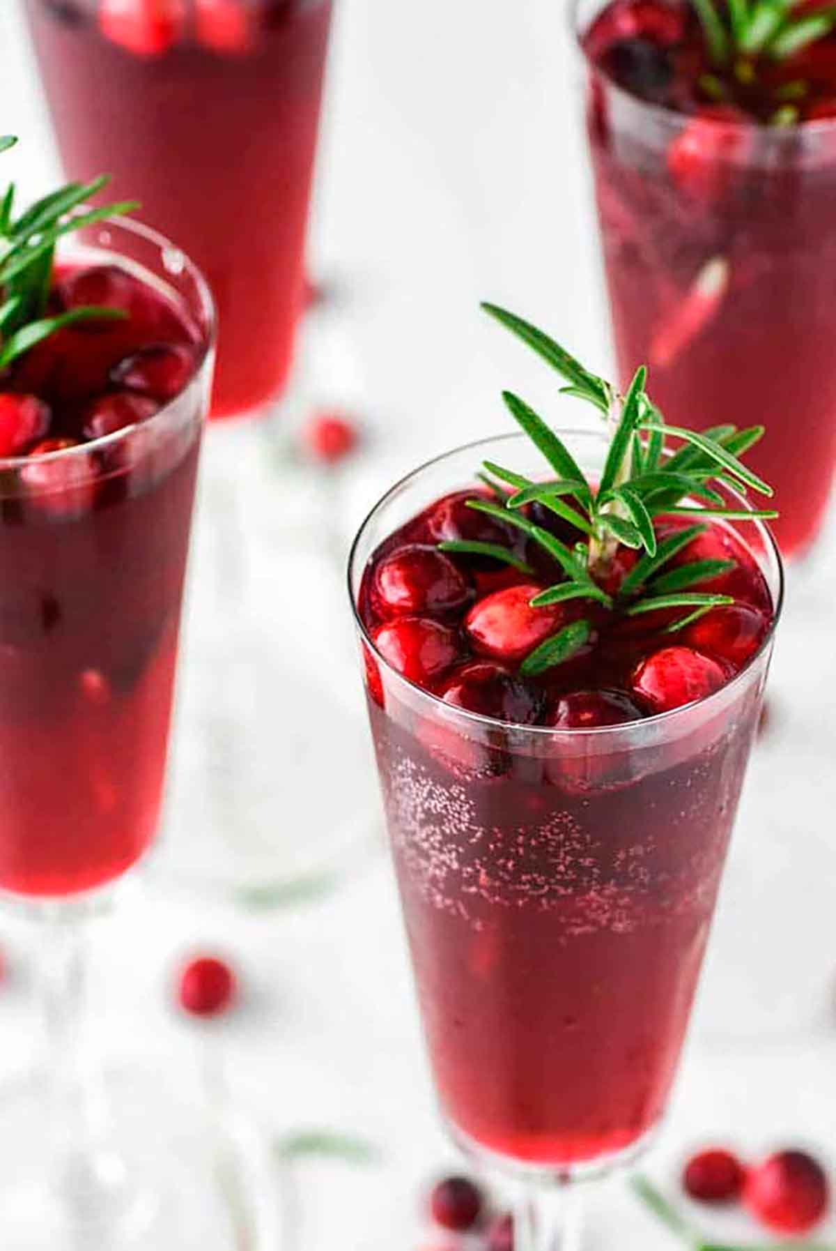 4 cranberry mimosas, garnished with cranberries and rosemary.