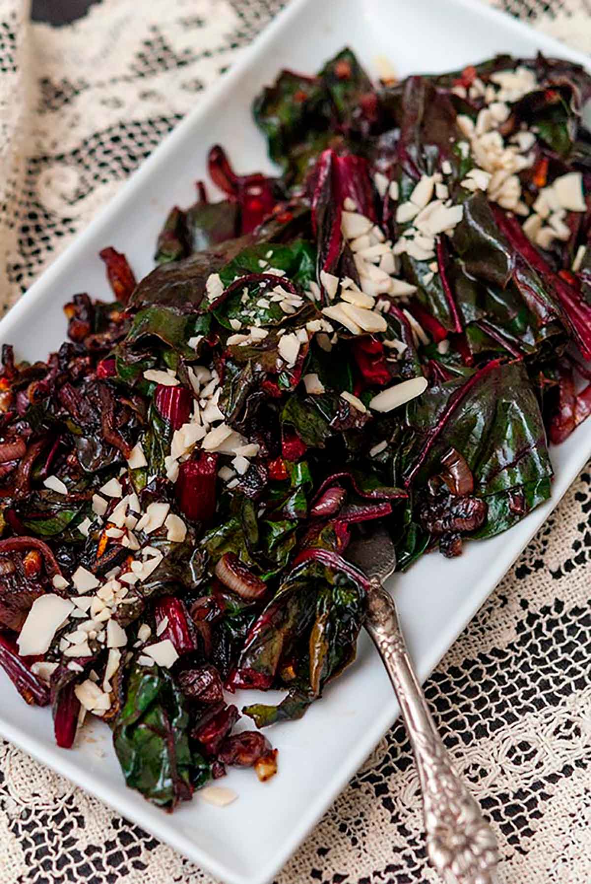 A plate of Swiss chard on a lace table cloth.