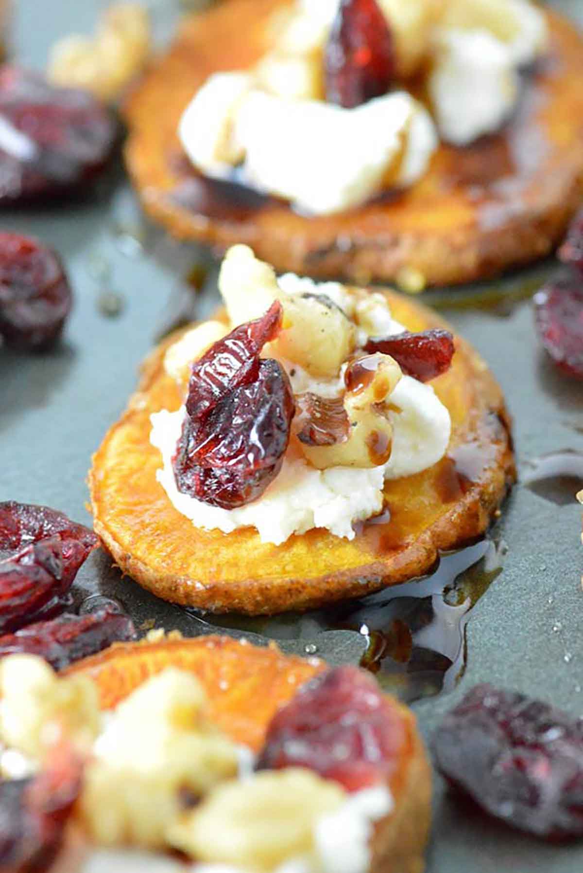 3 sweet potato rounds, garnished with cheese, cranberries and crushed nuts.