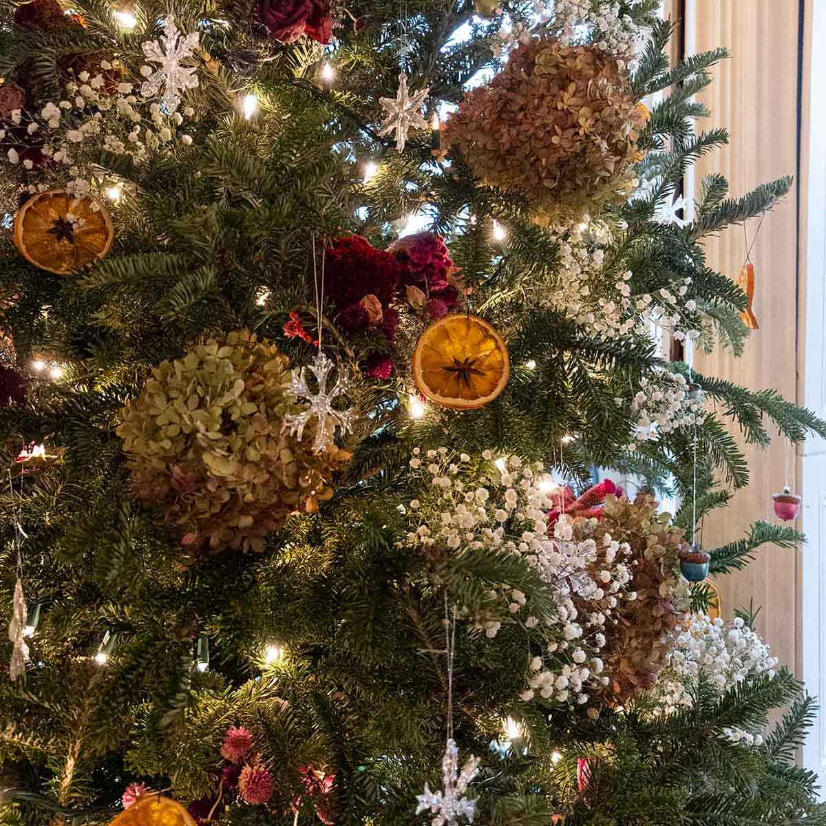 A Christmas tree, decorated with flowers, orange slices and lights.
