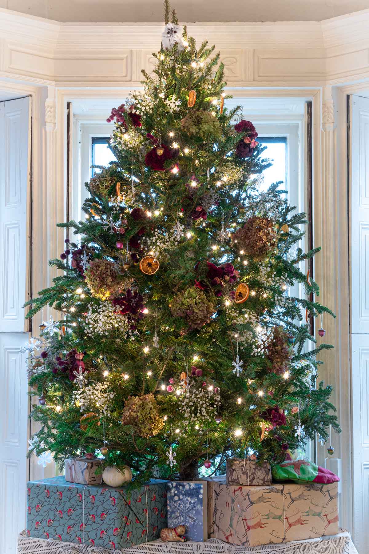 A Christmas tree, decorated with flowers, orange slices and lights.