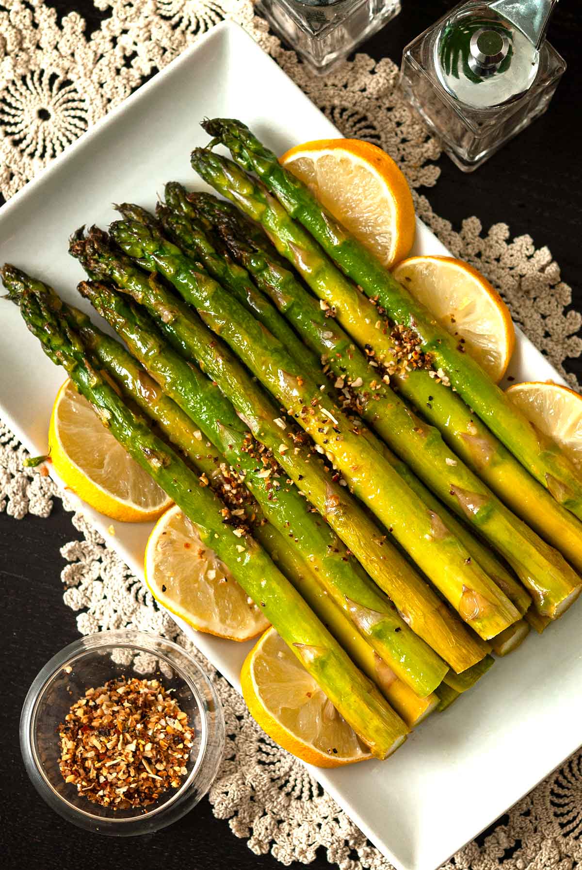 A stack of lemon asparagus on a plate, garnish with lemons.