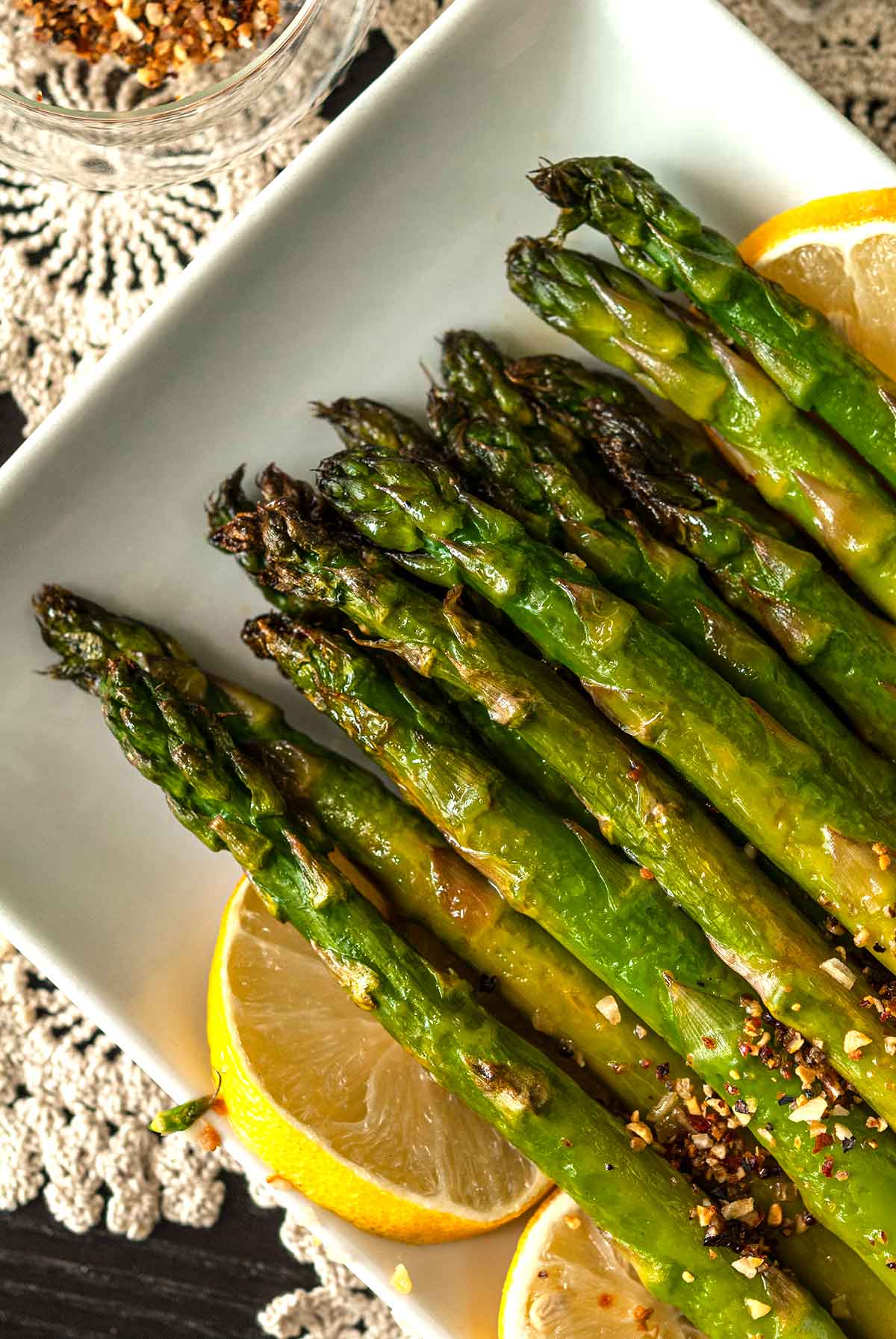 Crispy asparagus tips on a plate, garnished with lemons.