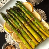 A stack of lemon asparagus on a plate, garnish with lemons.