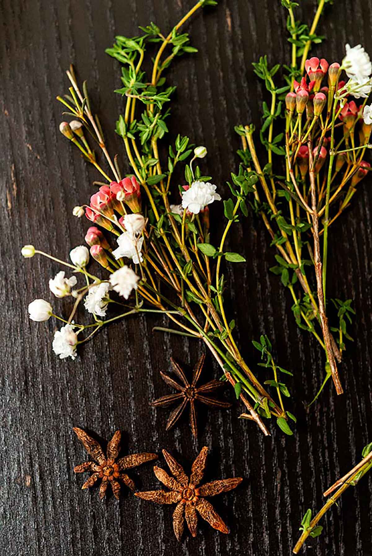 2 small bunches of herbs and flowers on a table with 3 star anise.