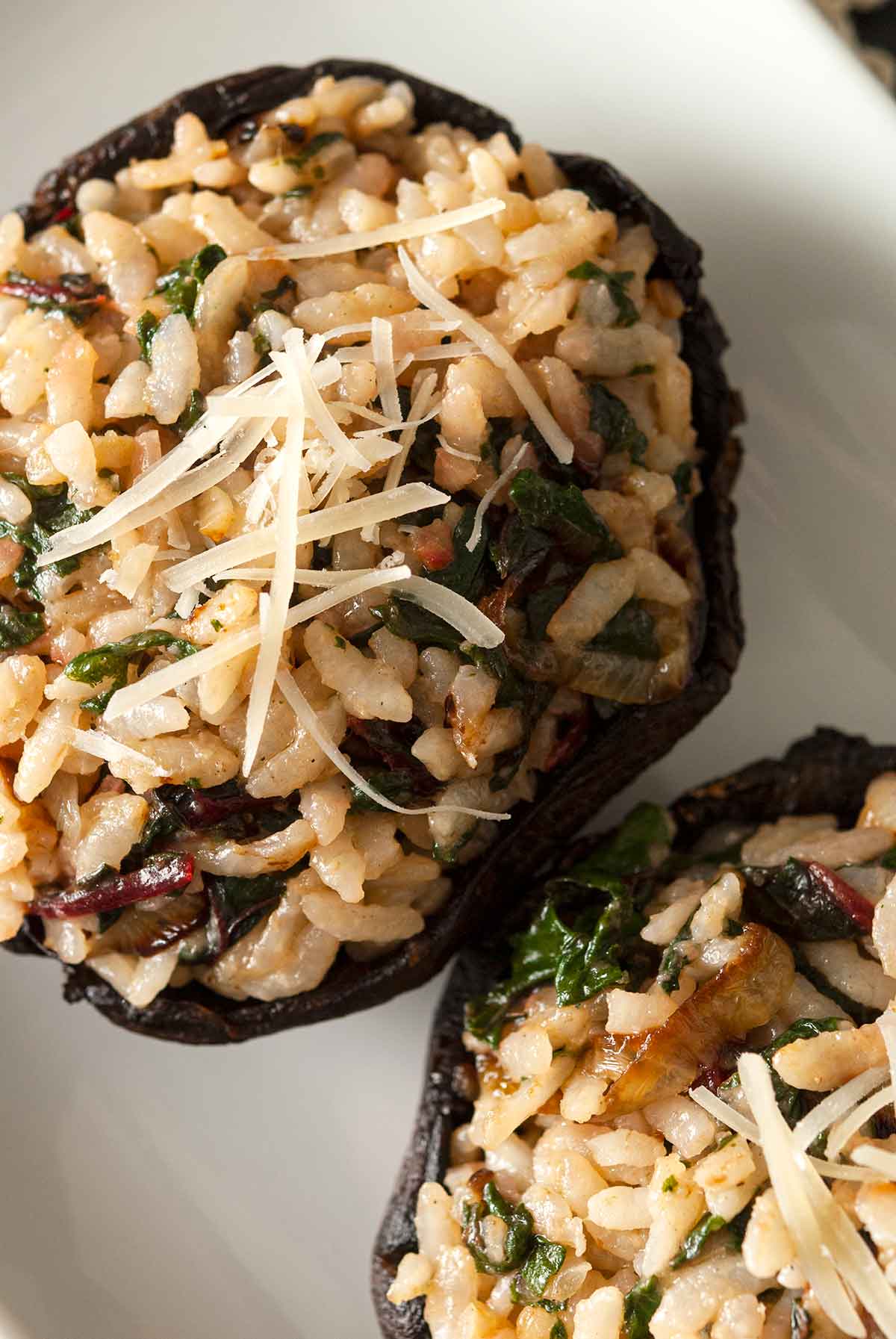 2 risotto-stuffed portobello mushrooms on a plate.