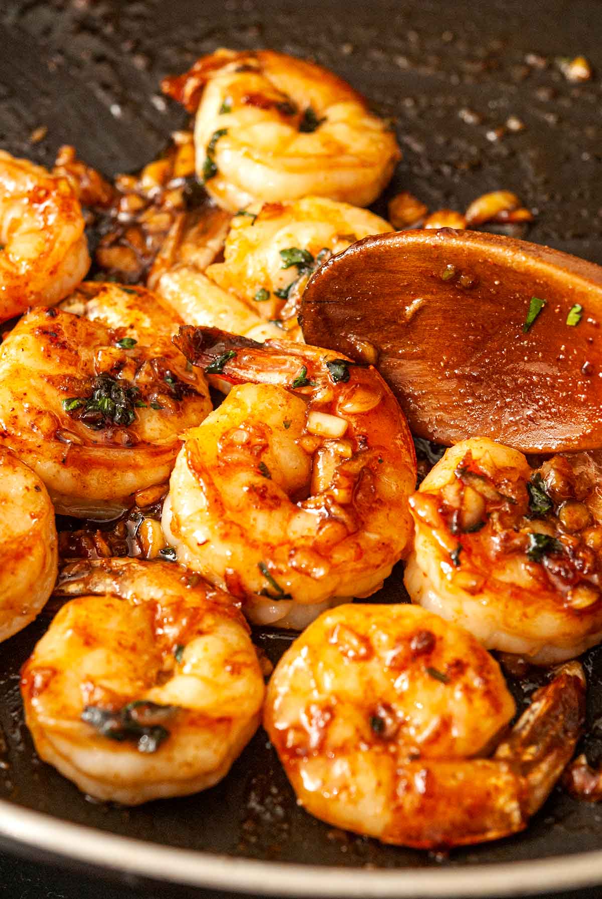 12 cooked shrimp in a pan with a wooden spoon.