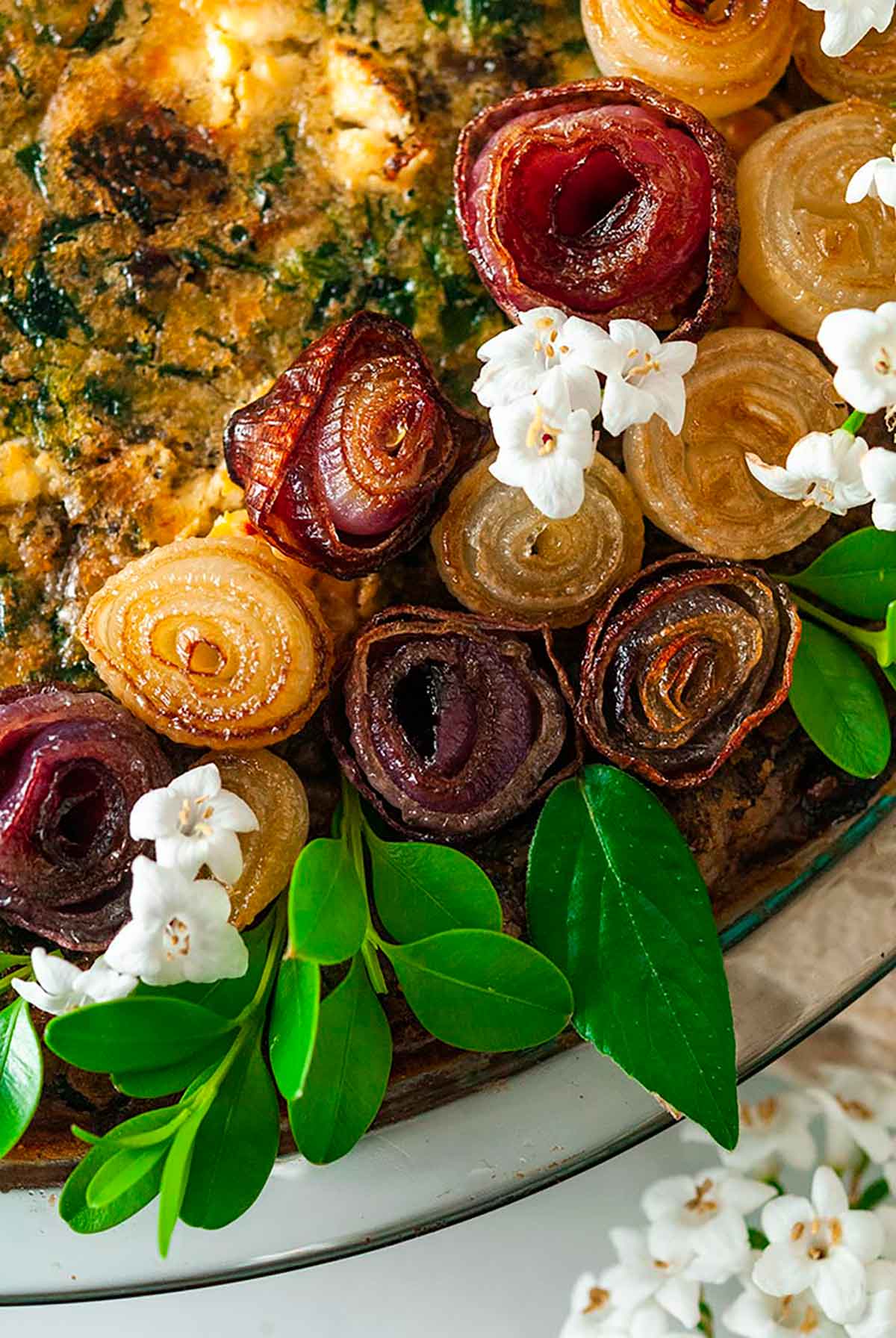 A quiche, garnished with pearl onion roses and little flowers.