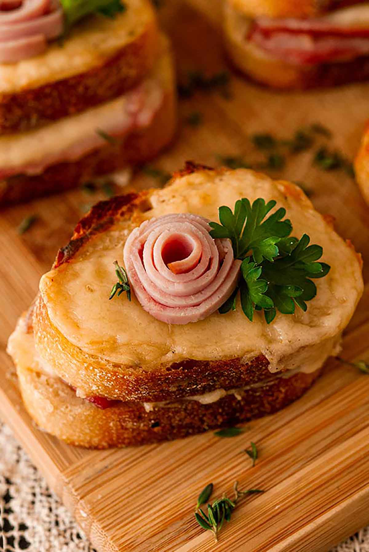 A mini croque monsieur with a small ham rose garnish and parsley on a decorative, antique plate.