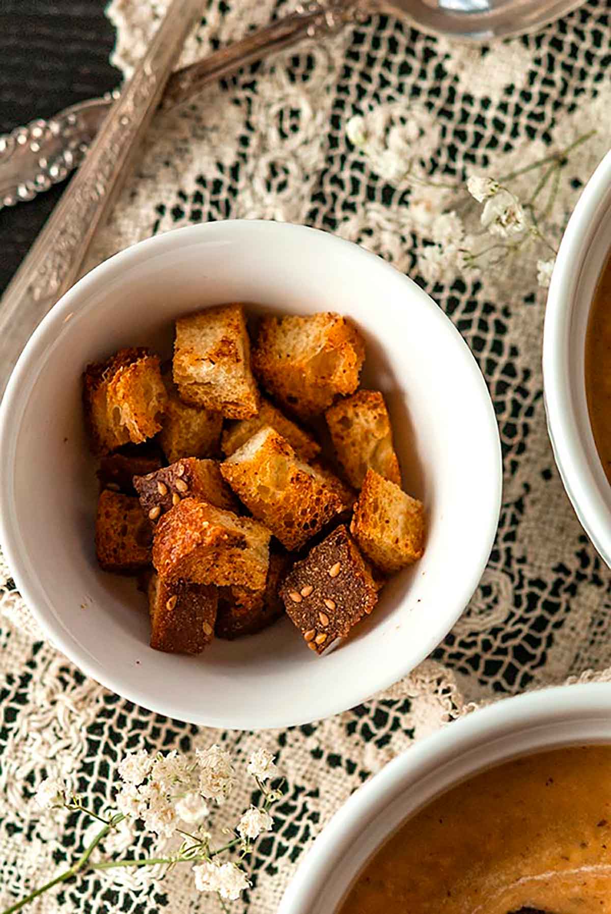 A small bowl of croutons on a lace table cloth.