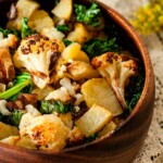 A wooden bowl of potato-cauliflower hash on a lace table cloth with flowers on the edges.