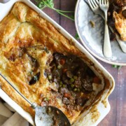 A rectangular baking plate of cottage pie next to a plate of it.