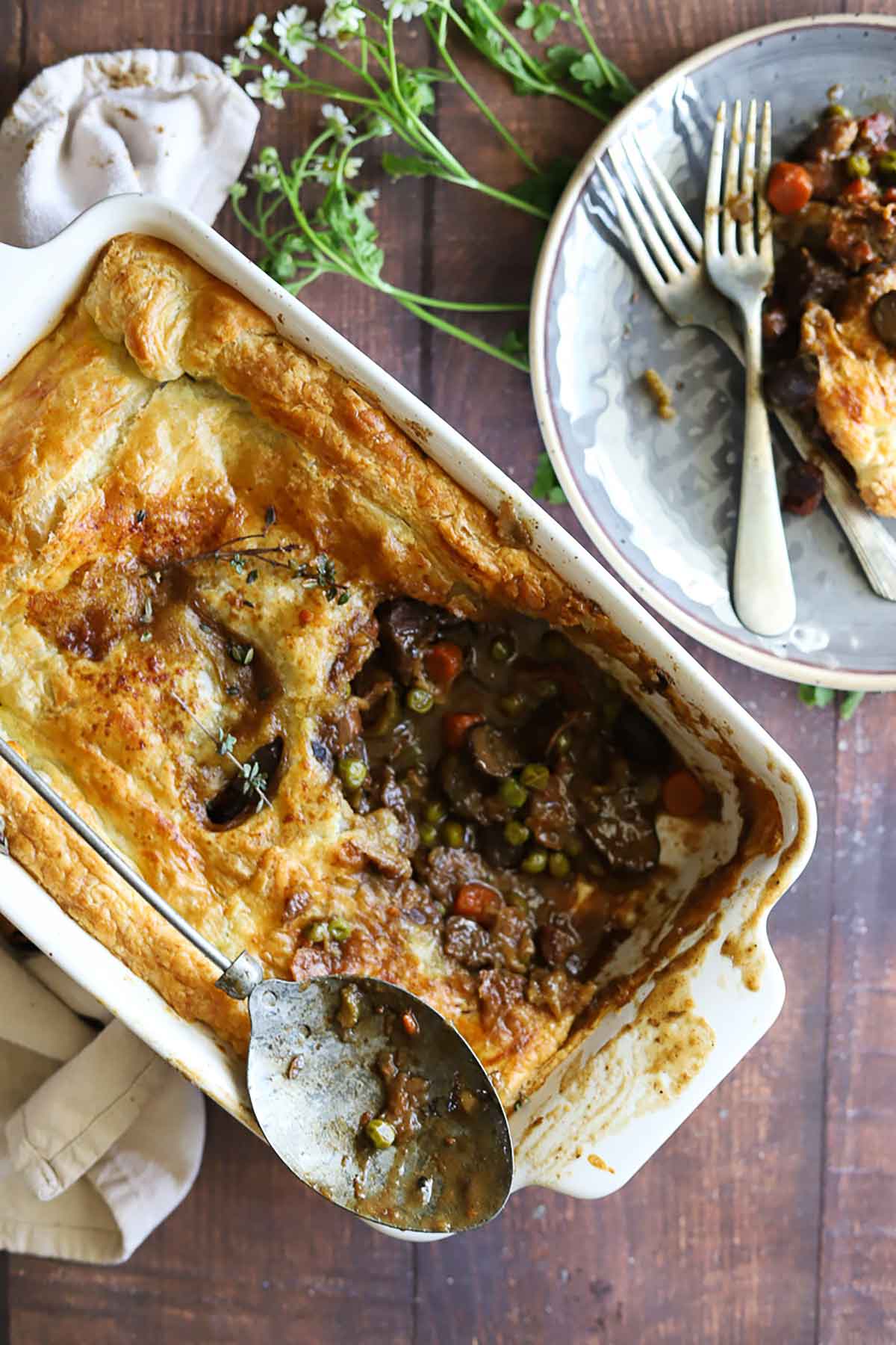 A rectangular baking plate of cottage pie next to a plate of it.