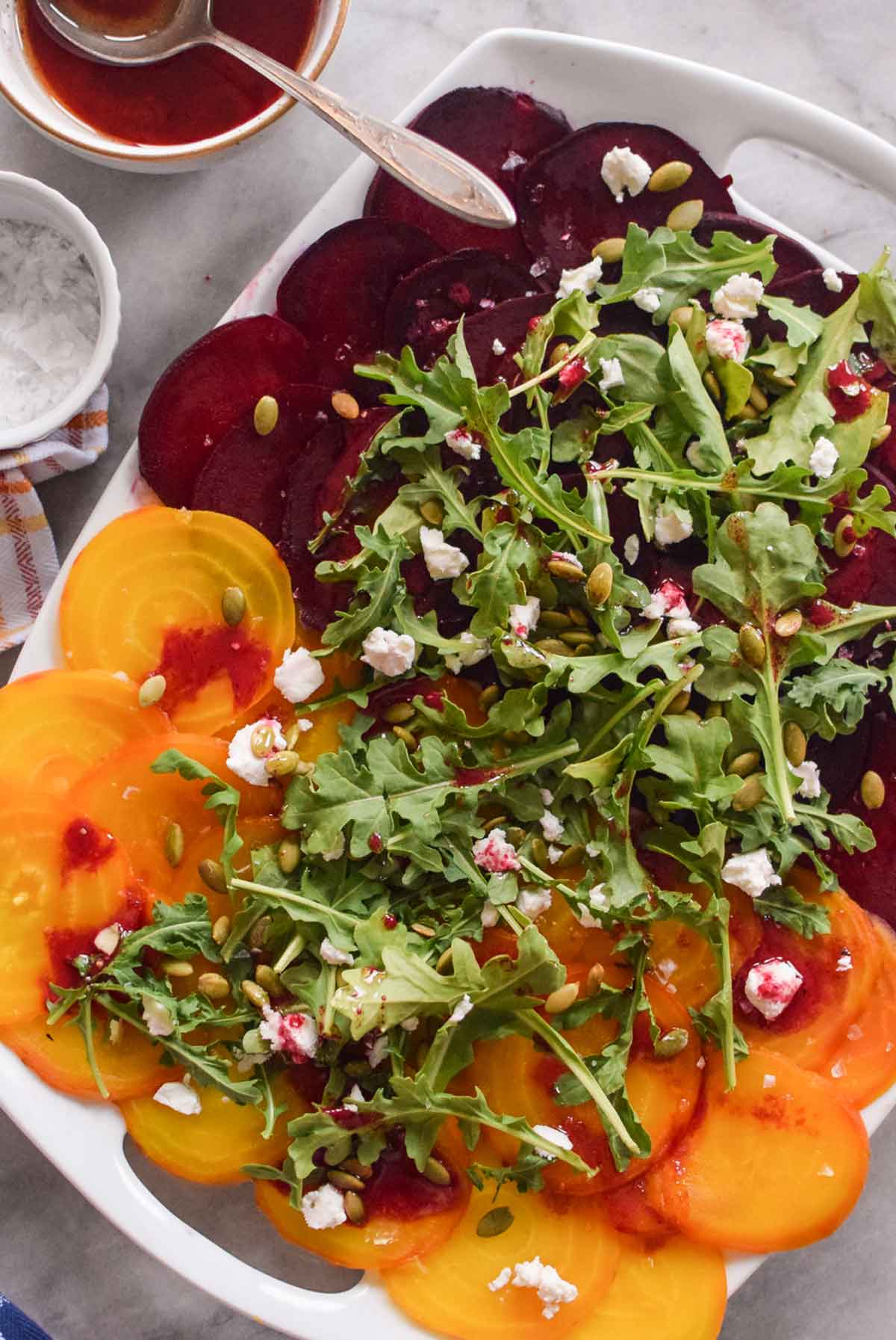 Sliced beets on a plate with arugula and pepitas.