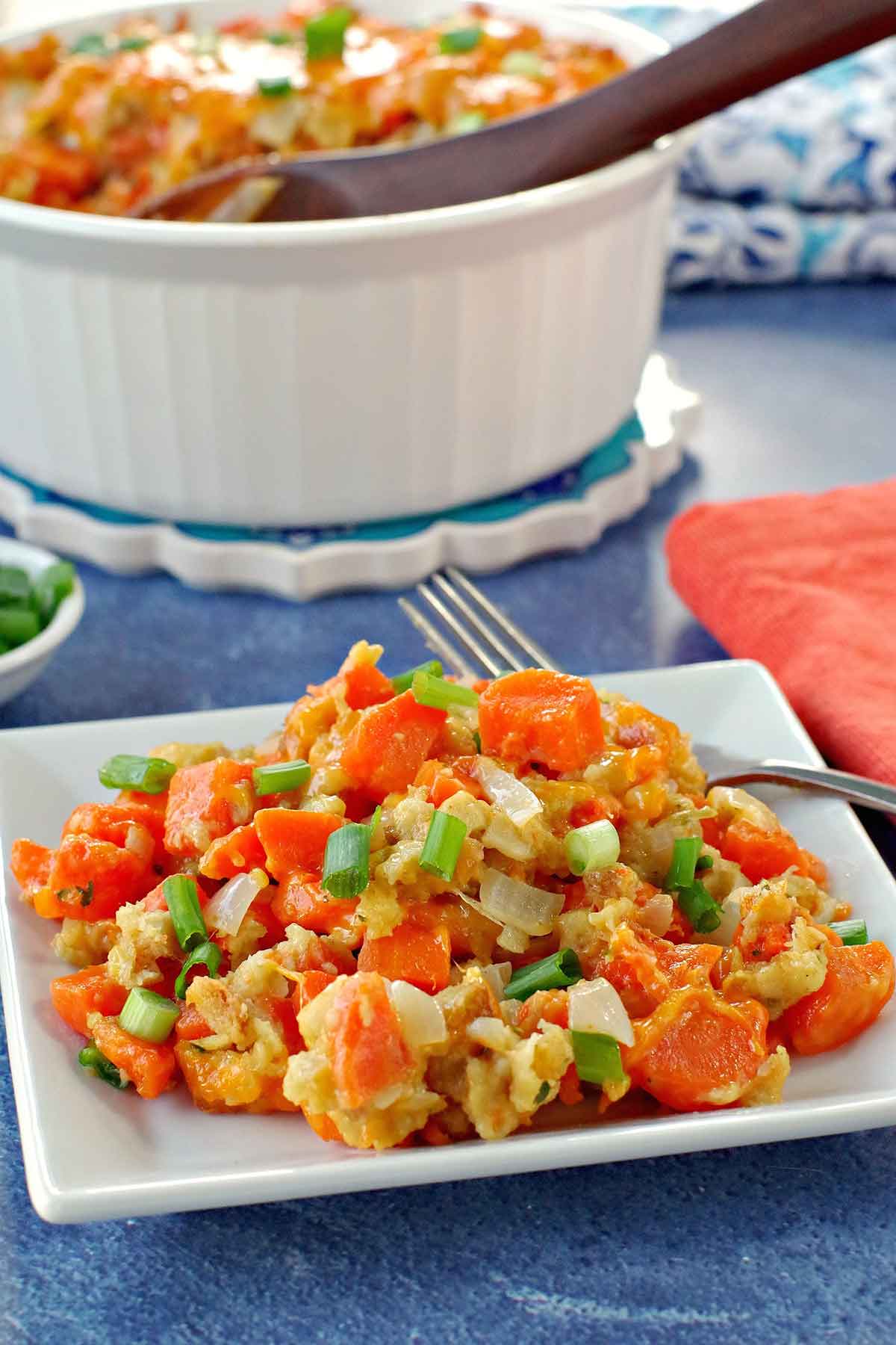 Carrot casserole on a plate with a bowl of casserole in the background.