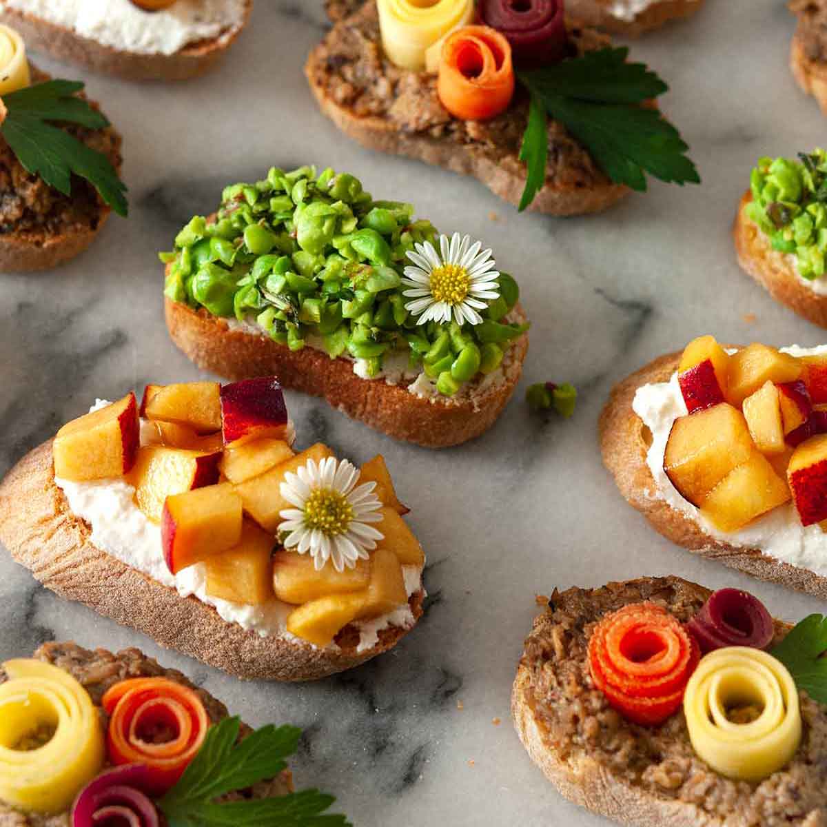 13 beautifully garnished crostini on a marble plate.