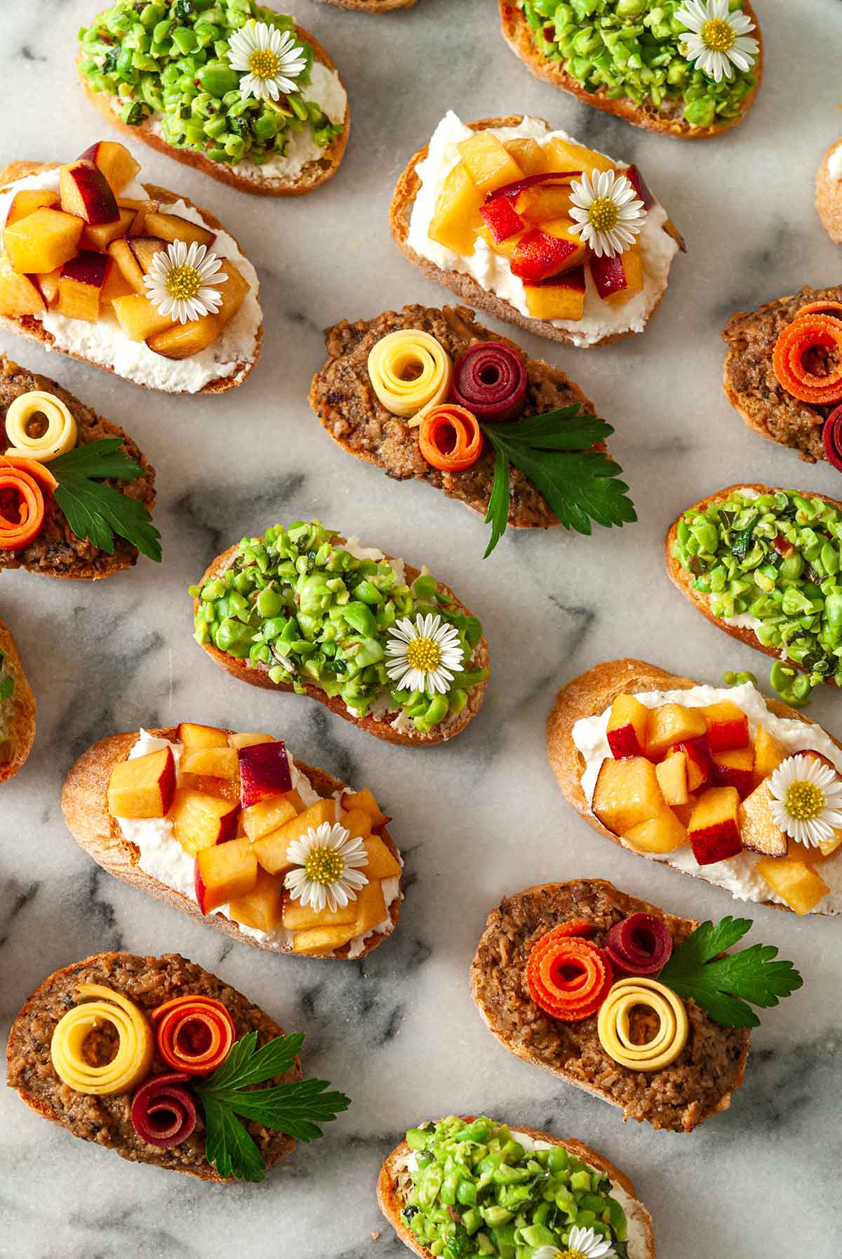 14 brightly colored crostini on a marble slate.