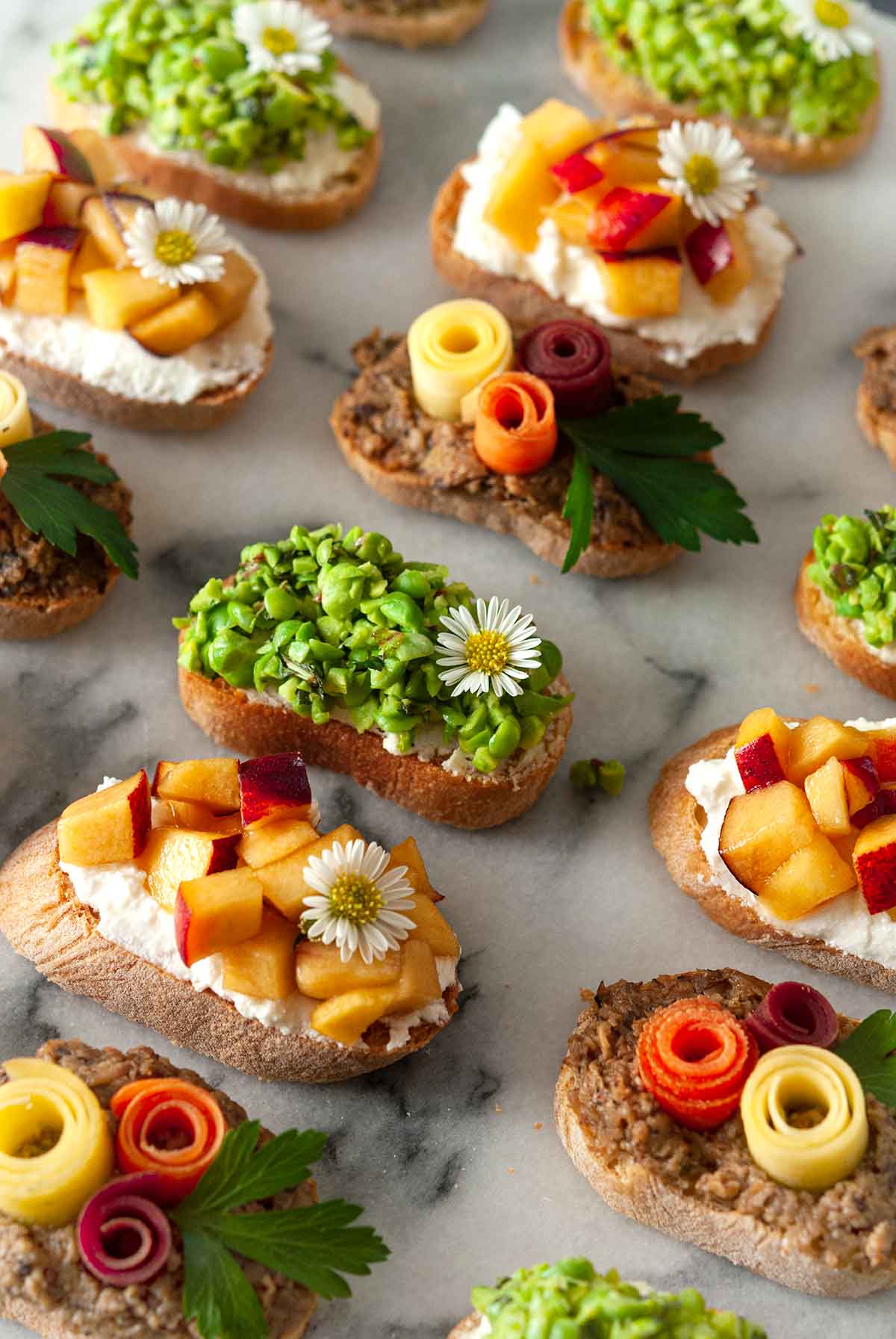 13 beautifully garnished crostini on a marble plate.