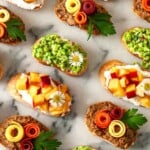 9 brightly colored crostini on a marble slate.