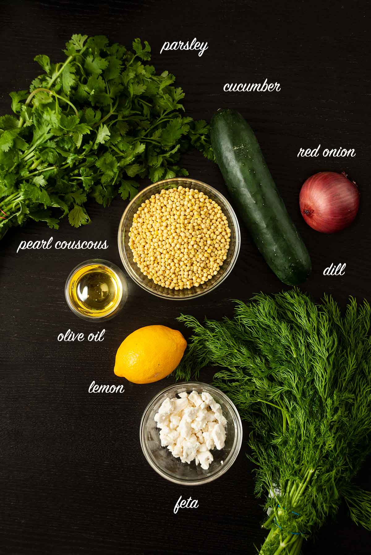 Ingredients on a table for lemon turmeric pearl couscous with text labels of each ingredient.