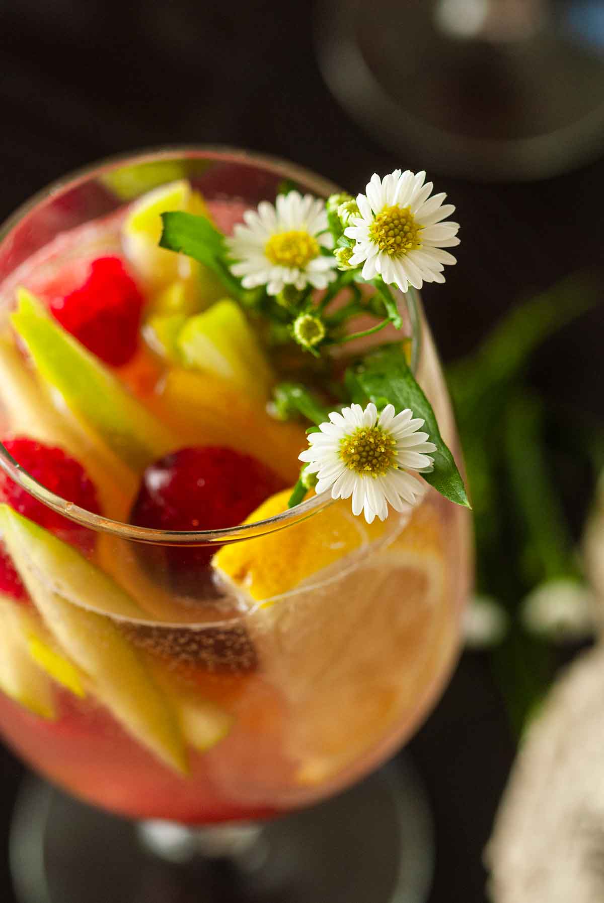 The daisy and fruit garnish in a glass of sake sangria.