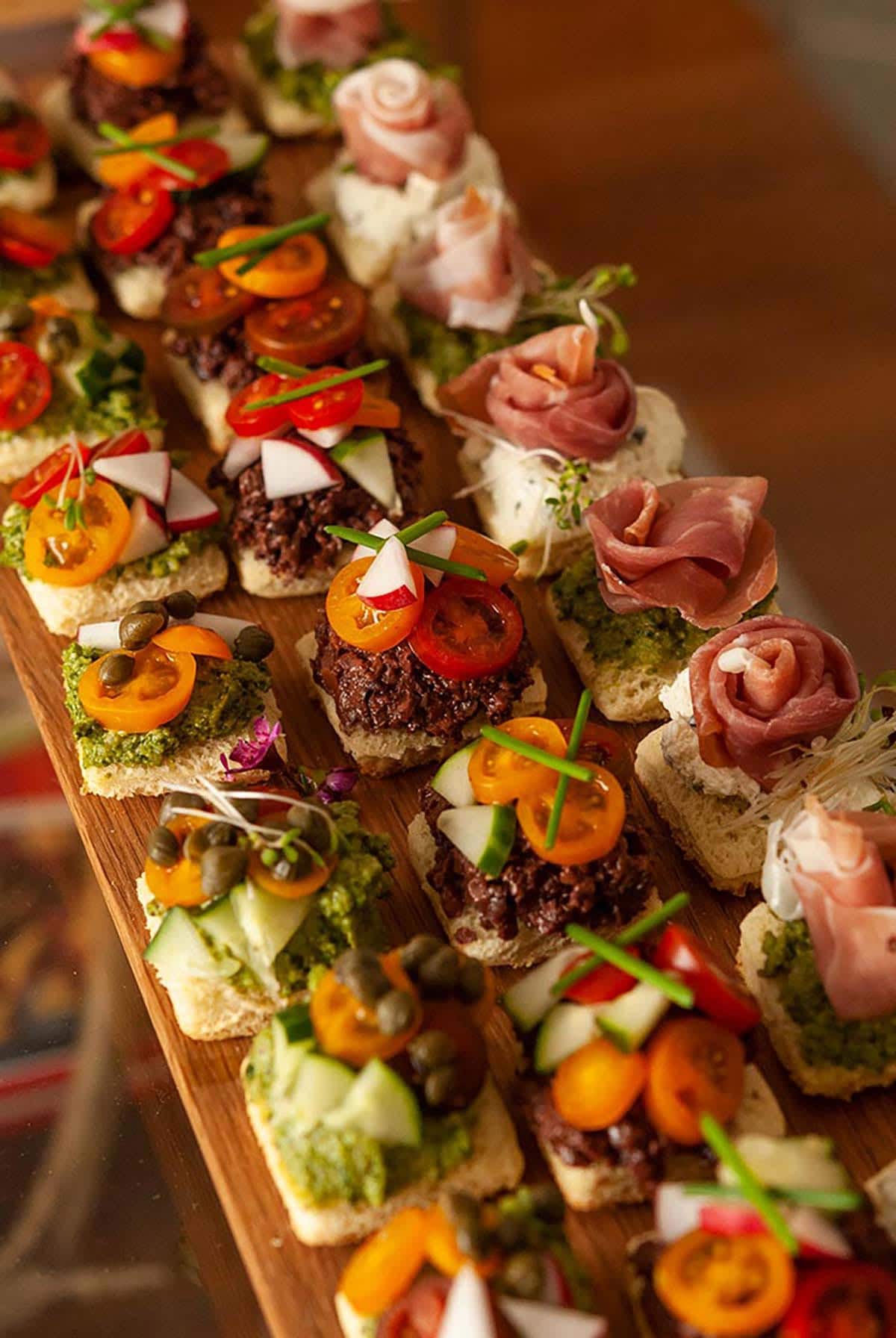 An appetizer tray of 24 canapés in 3 different styles.