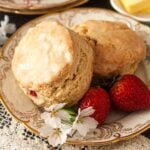 2 scones on a decorative plate with flowers and strawberries.