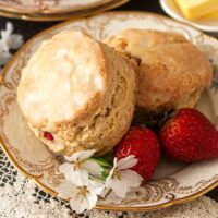 2 scones on a decorative plate with flowers and strawberries.