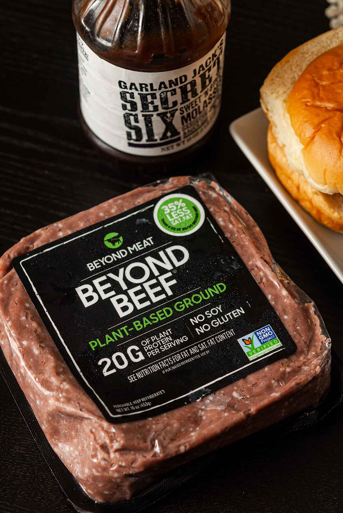 A package of Beyond Beef beside barbecue sauce and slider buns.