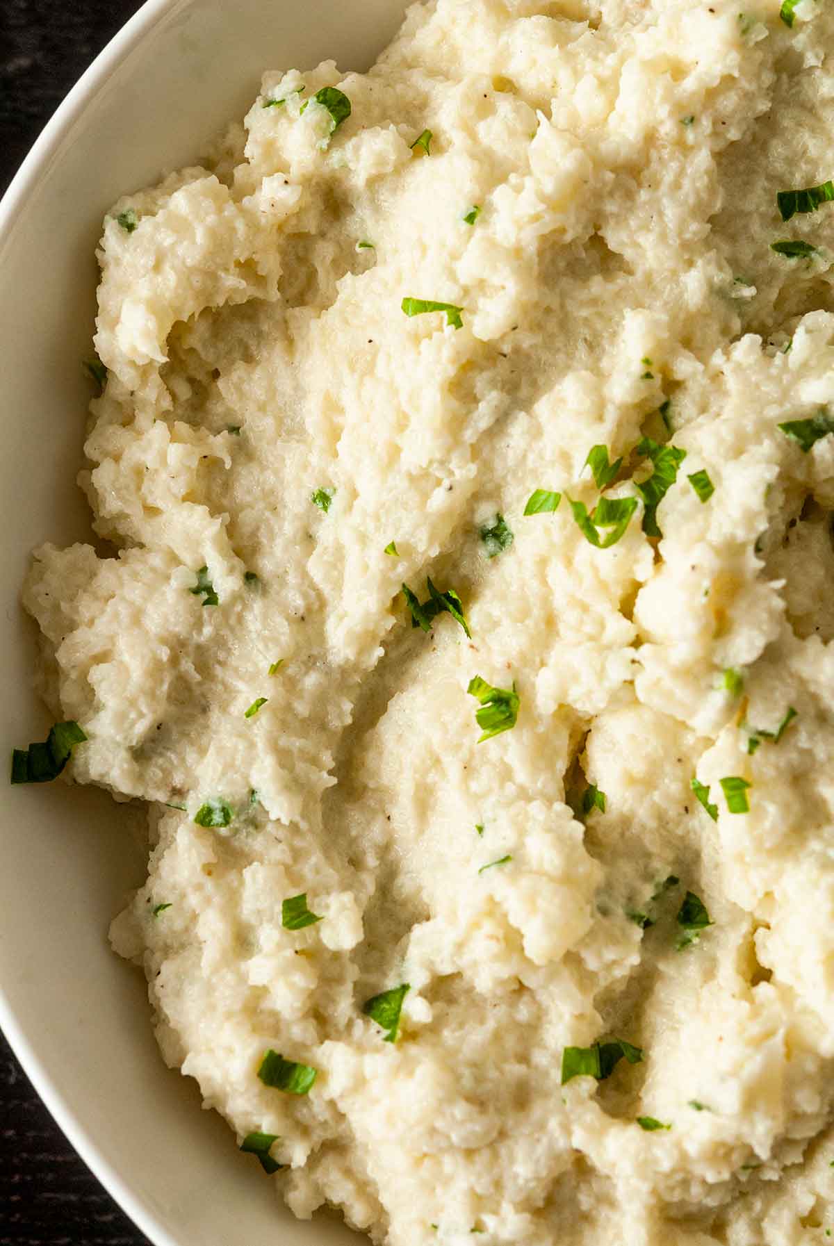A bowl of garlic-parmesan mashed cauliflower with finely-diced parsley.