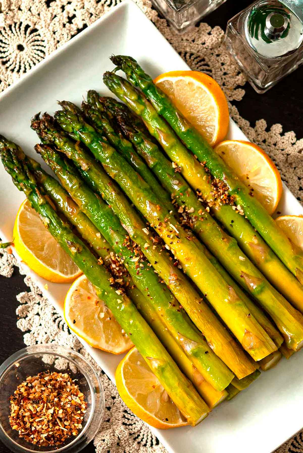 A stack of lemon asparagus on a plate, garnish with lemons.