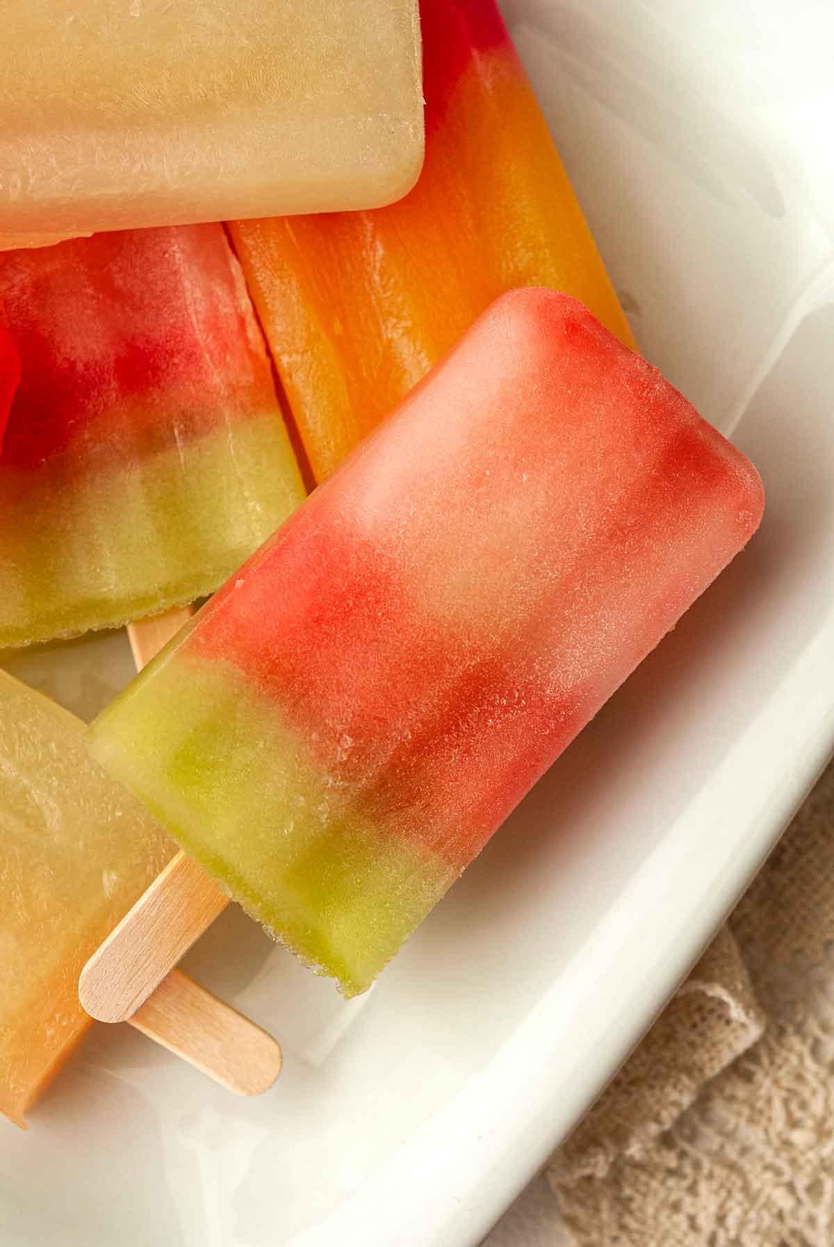 5 White Claw ice pops stacked on a white plate.