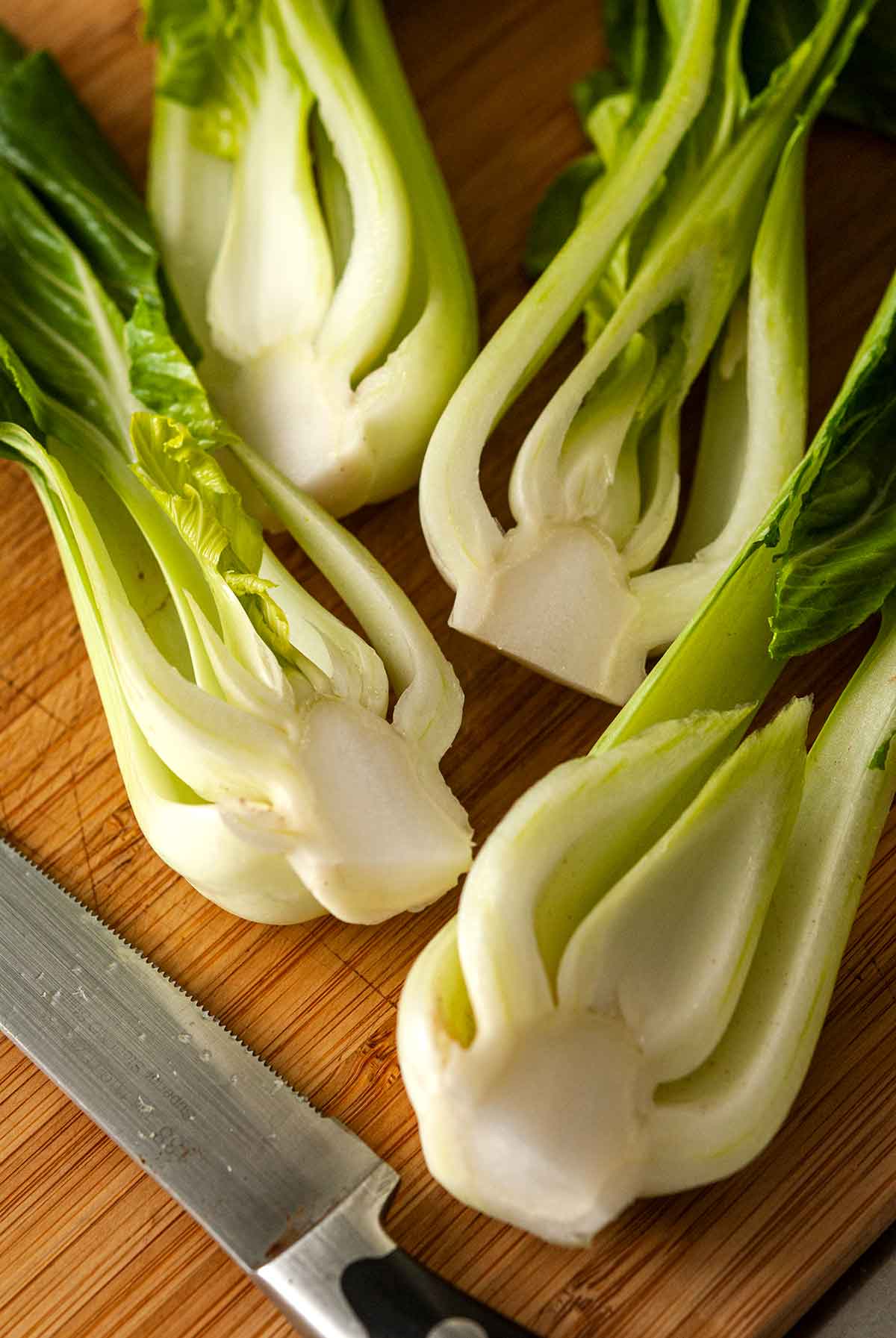 4 slices of baby bok choy on a cutting board.